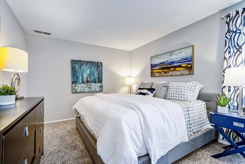 A bedroom with a bed, nightstand, and two lamps.