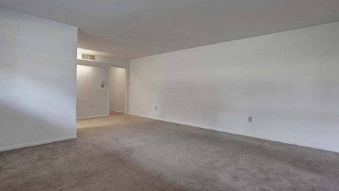A large empty room with a carpeted floor and white walls.