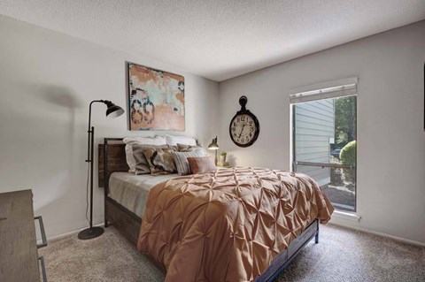 A bedroom with a bed, lamp, and clock on the wall.
