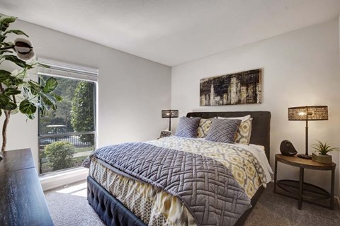 A bedroom with a large bed and a potted plant.