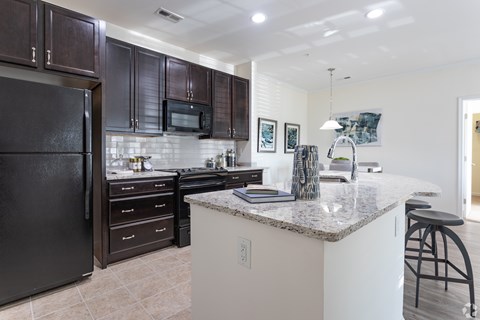 A kitchen with a black refrigerator and white countertops.