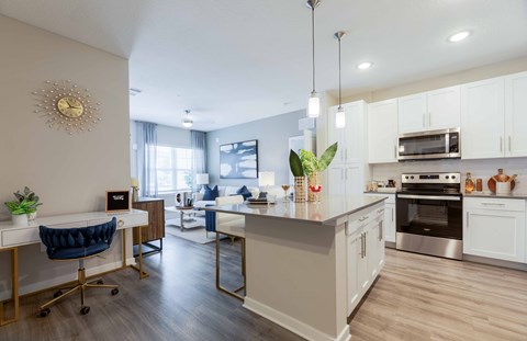 A modern kitchen with a blue chair and a dining area in the background.