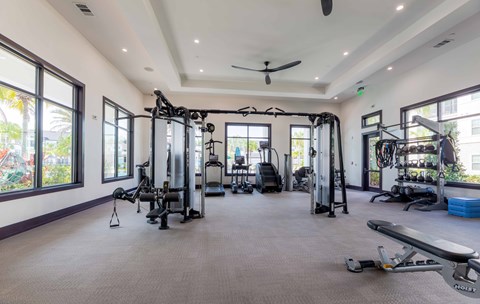 A spacious gym with a variety of equipment and a ceiling fan.