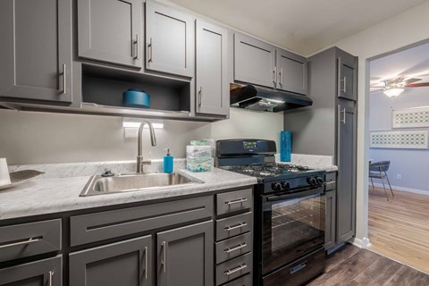 A kitchen with a black stove top oven and a marble counter top.