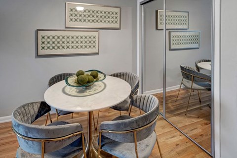 A round table with a bowl of fruit on it and chairs around it.