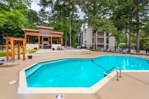 A large swimming pool with a diving board and a pavilion.