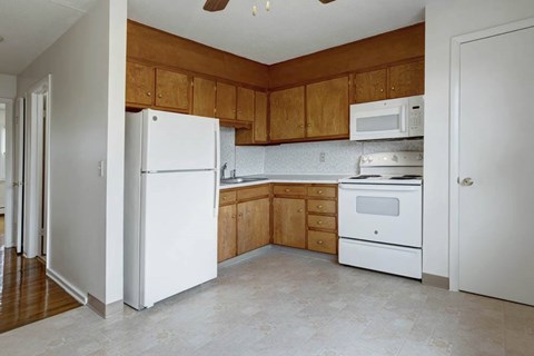 A kitchen with white appliances and wooden cabinets.