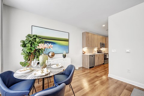 A dining room with a table set for two and a painting on the wall.
