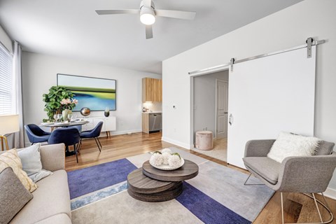 A living room with a grey couch, a blue chair, a grey armchair, a coffee table, and a painting on the wall.