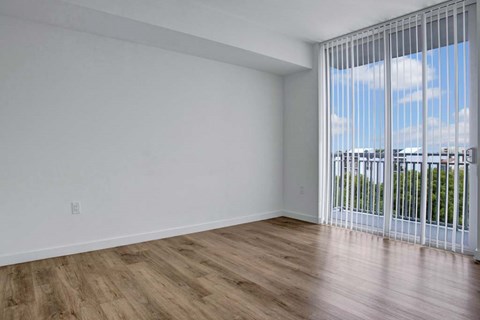 A room with a sliding glass door leading to a balcony.