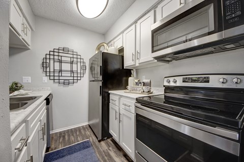 A kitchen with a black refrigerator, stove, and microwave.