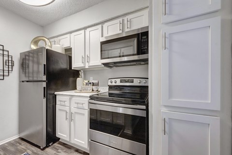 A kitchen with white cabinets and a black fridge.