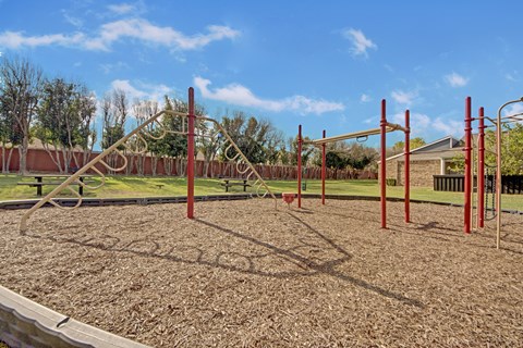 A playground with a red swing set and a sandbox.