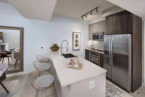 A modern kitchen with a white island and stainless steel appliances.