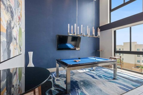 A pool table in a room with a television and a painting on the wall.