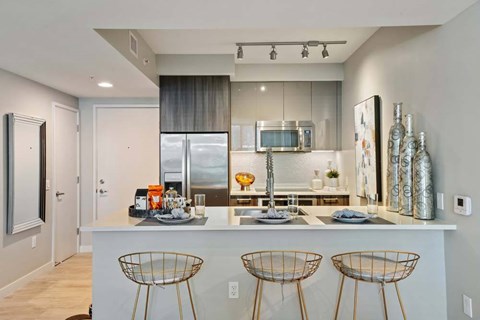 A modern kitchen with a white island and stainless steel appliances.