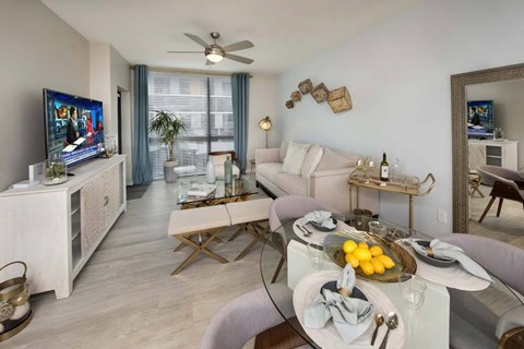 A living room with a white sofa, a glass table, and a TV on a cabinet.