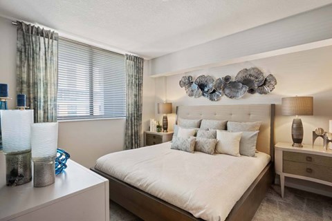 A bedroom with a large bed, a nightstand, and a side table.
