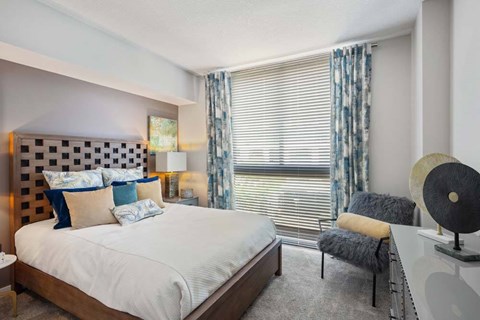 A bedroom with a large bed and a chair.