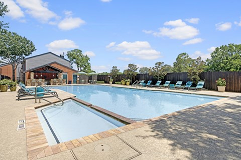 A pool with a wooden deck and sun loungers.