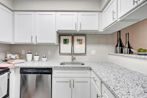A kitchen with white cabinets and a granite countertop.