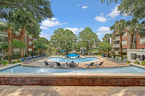A pool surrounded by trees and chairs.