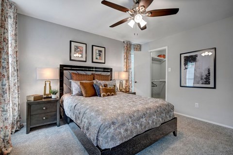 A bedroom with a bed, nightstand, and a ceiling fan.
