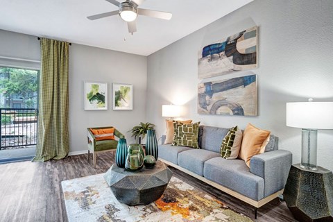 A living room with a grey couch, a coffee table, and a painting on the wall.