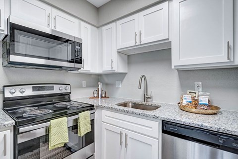 A modern kitchen with white cabinets and a black stove top.