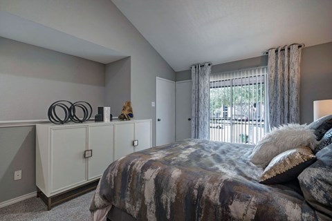 A bedroom with a large bed and a window with curtains.