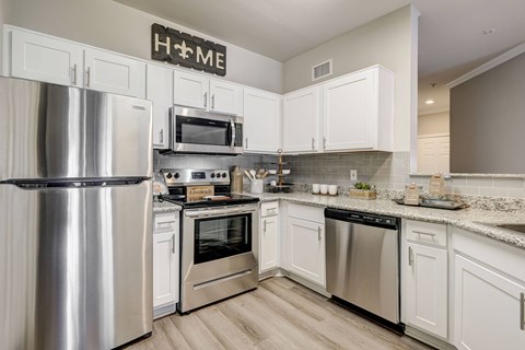 A modern kitchen with a stainless steel refrigerator and white cabinets.