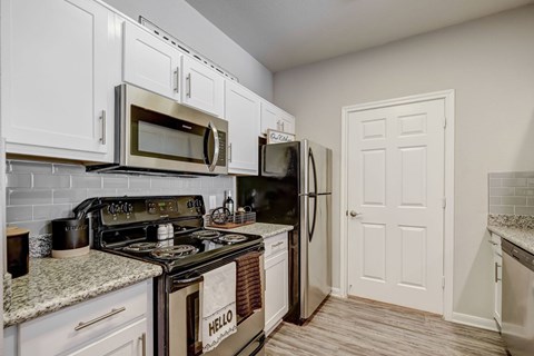 A kitchen with white cabinets and a black stove top.