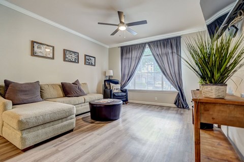 A living room with a beige couch, a coffee table, and a ceiling fan.