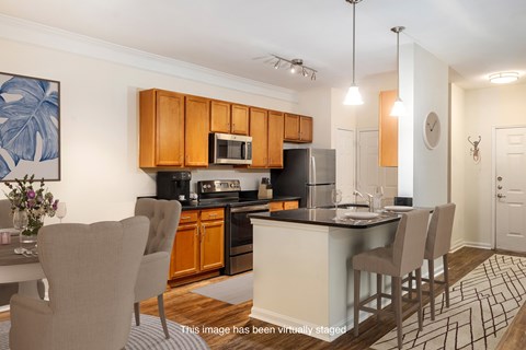 A kitchen with brown cabinets and a black fridge.