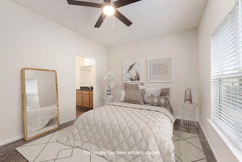 A bedroom with a large bed and a ceiling fan.