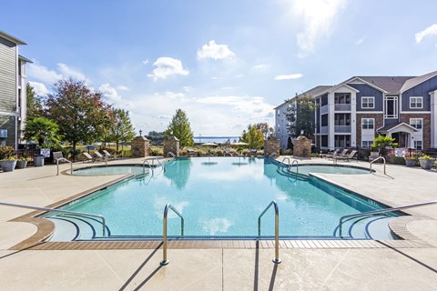 A large outdoor swimming pool with a sunny sky in the background.