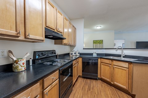 A kitchen with wooden cabinets and black countertops.