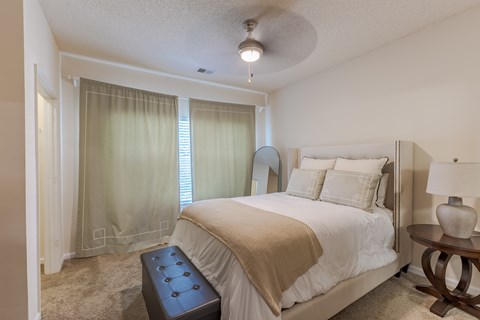 A bedroom with a large bed and a ceiling fan.