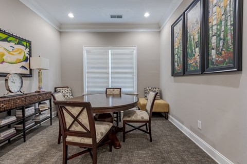 A dining room with a table set for two and a painting on the wall.
