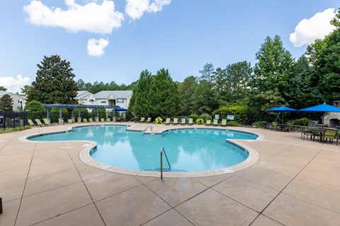 A large outdoor swimming pool surrounded by trees and a fence.