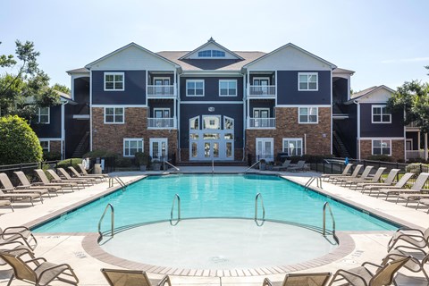 A large apartment complex with a pool in front.