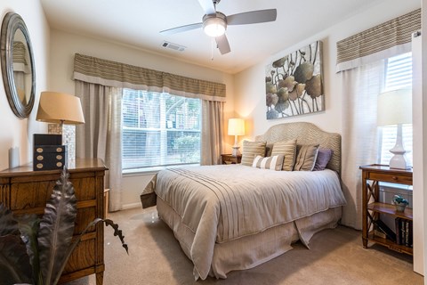 A bedroom with a large bed and a ceiling fan.