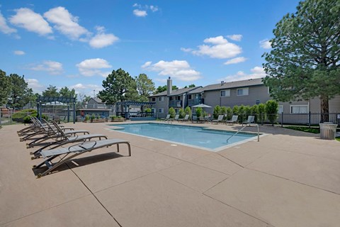 A pool with sun loungers and a building in the background.
