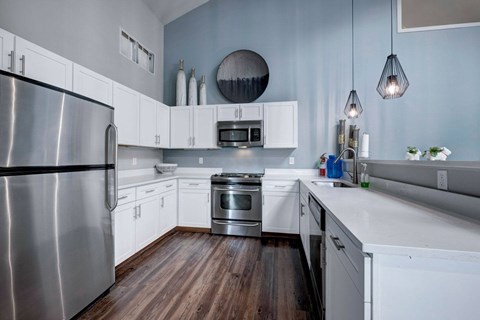 A modern kitchen with a stainless steel refrigerator and wooden floors.