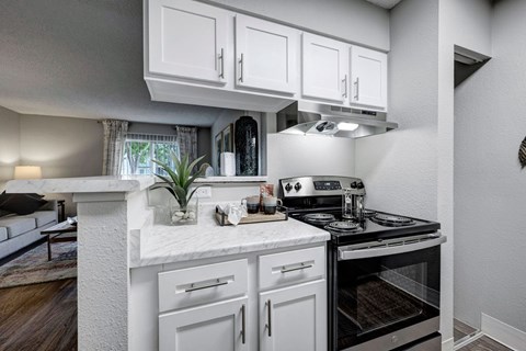 A modern kitchen with white cabinets and a black stove top oven.
