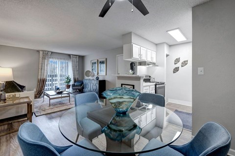A modern dining room with a glass table and blue chairs.