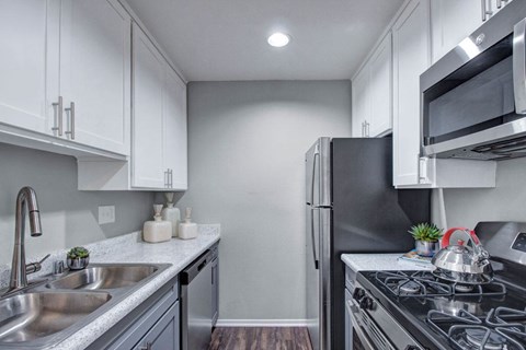 A kitchen with a black refrigerator and stove top oven.