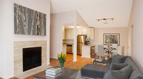 A living room with a grey couch, a fireplace, and a painting on the wall.