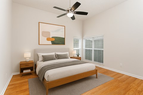 A bedroom with a bed, a ceiling fan, and a painting on the wall.