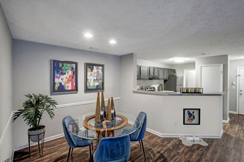 A dining room with a glass table and blue chairs.